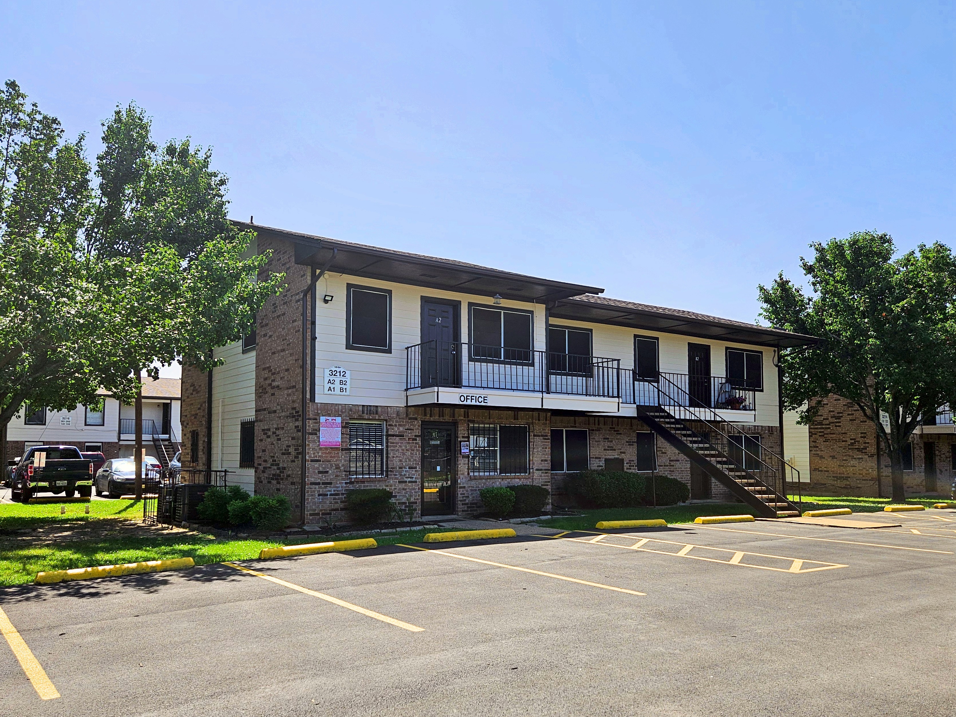 Two-story Autumn Run building with the leasing office, an outdoor staircase and a parking lot in front