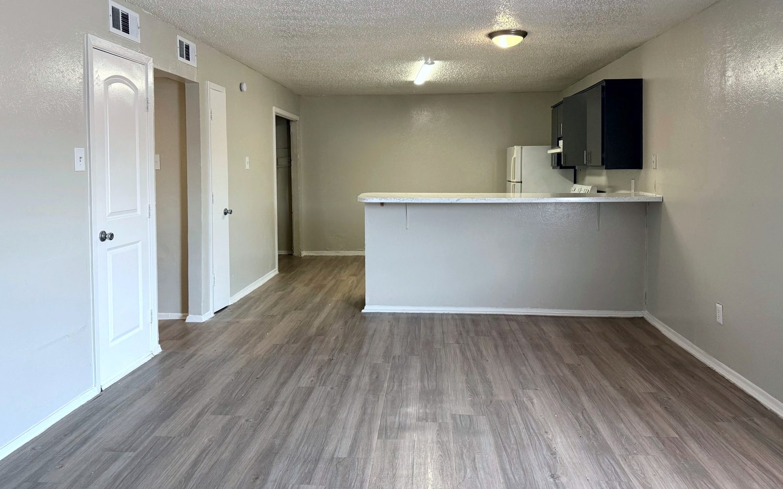 Living room with vinyl plank floors opening to a kitchen with a breakfast bar