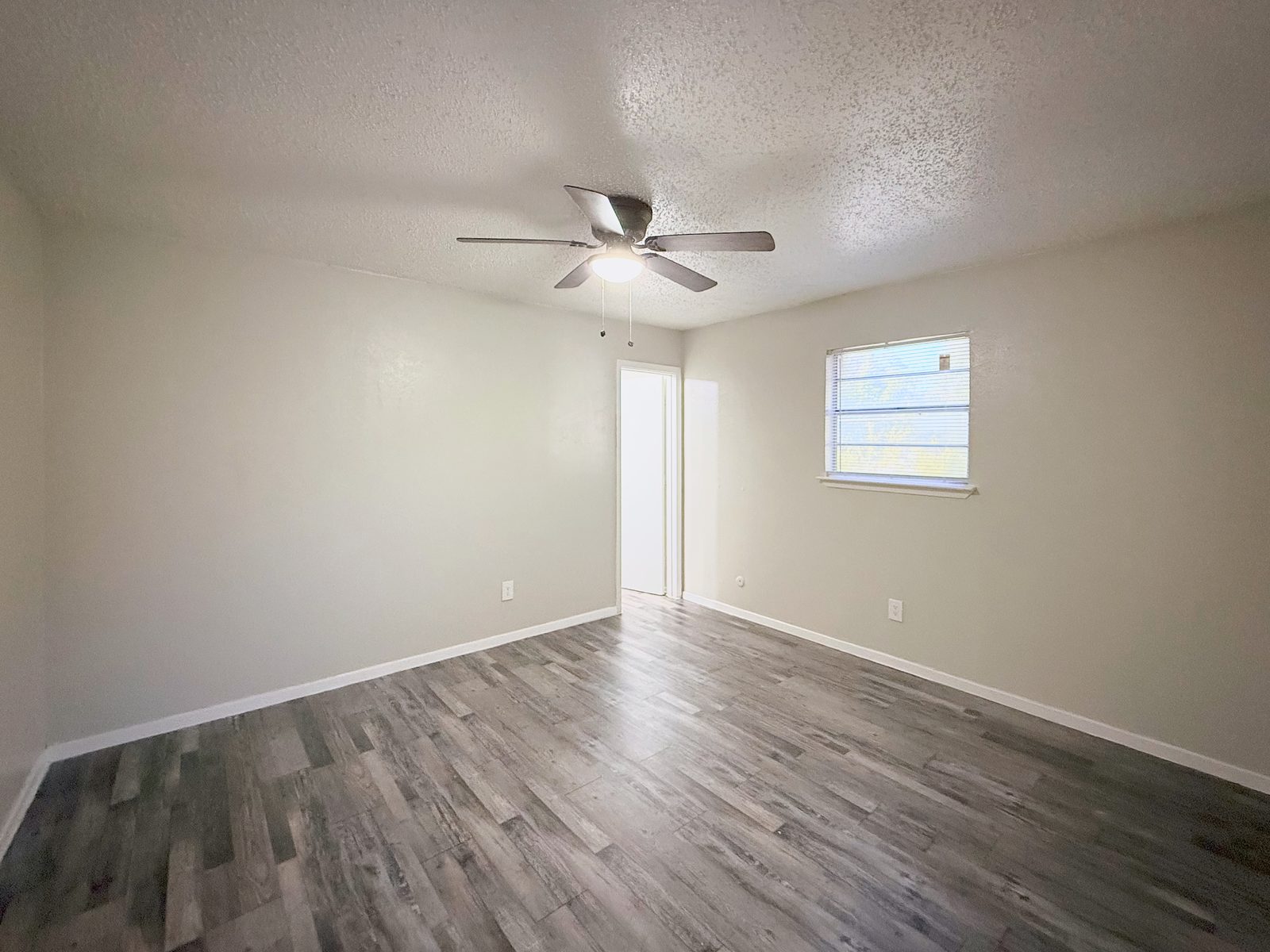 Bedroom with ceiling fan, window, wood-look floor and doorway to a closet