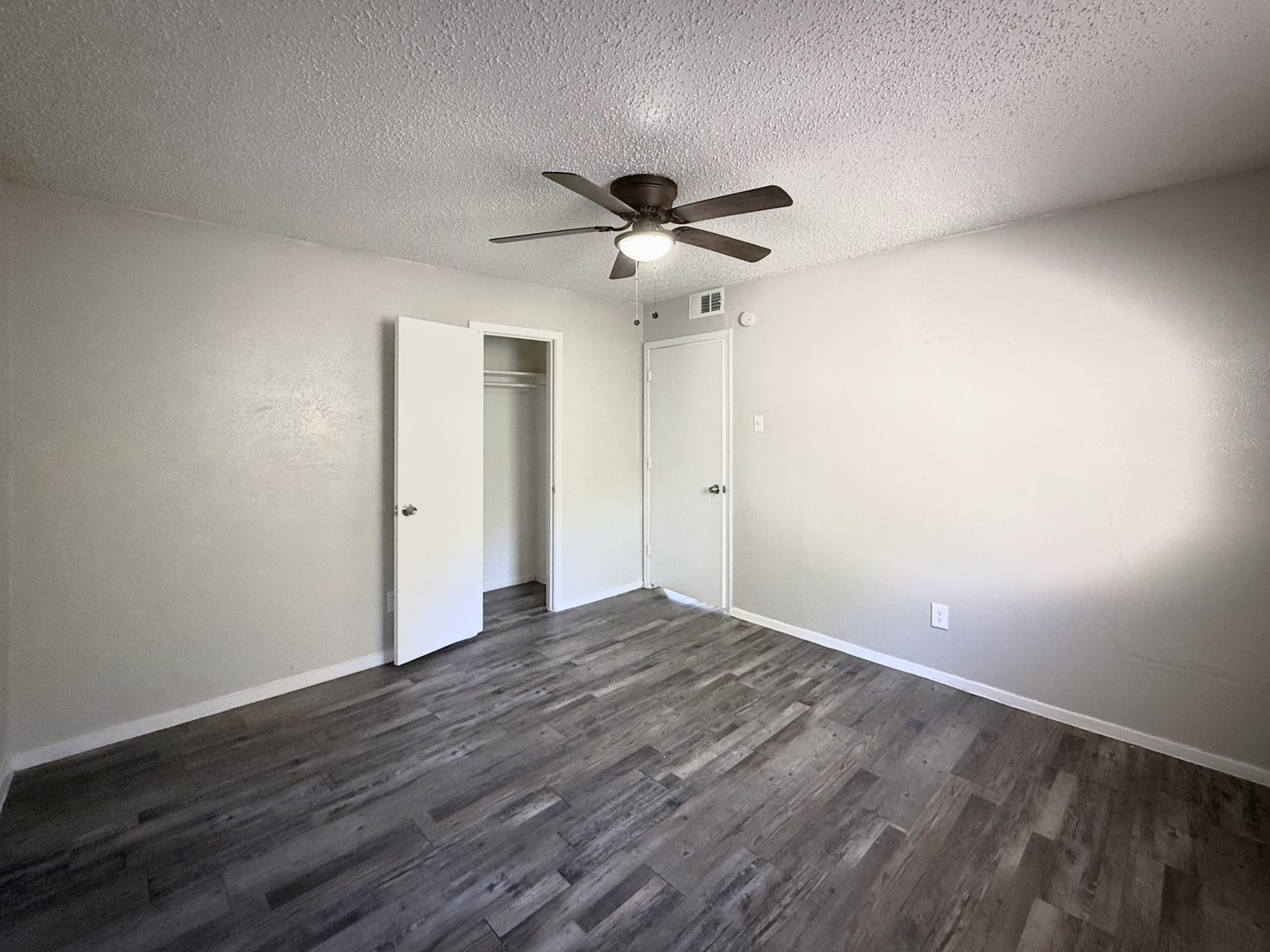 Bedroom with ceiling fan, open closet, entry door and wood-look floor